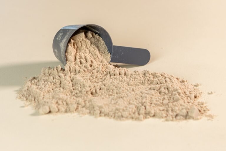 A clean scoop of white supplement powder on a table, evoking creatine and everyday supplementation