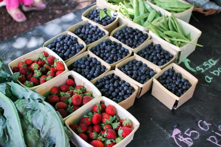 Fresh strawberries, blueberries, and peas at a market stall, evoking whole-food fiber sources