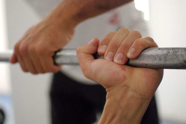A person gripping a loaded barbell bar, evoking grip strength and general training